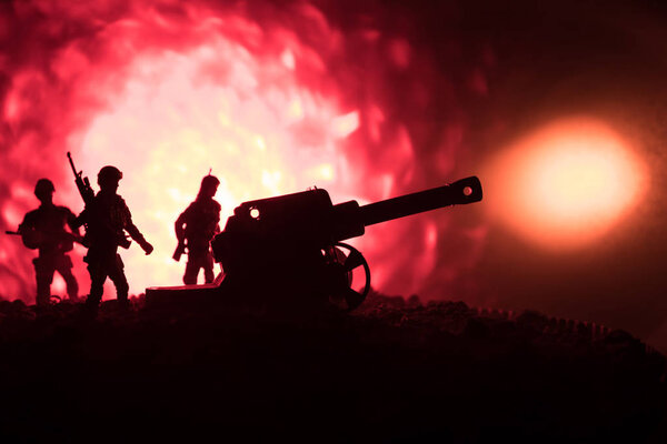 Battle scene with arillery and standing soldiers. Silhouette of old field gun standing at field ready to fire. With colorful dark foggy background.