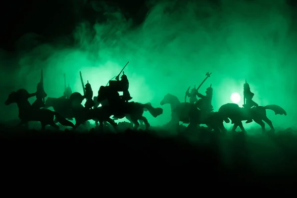 Middeleeuwse slag scène met de cavalerie en infanterie. Silhouetten van figuren als afzonderlijke objecten, strijd tussen krijgers op donker getinte mistige achtergrond. Nachtbeeld. — Stockfoto