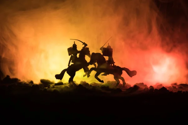 Escena de batalla medieval con caballería e infantería. Siluetas de figuras como objetos separados, lucha entre guerreros sobre fondo de niebla tonificado oscuro. Escena nocturna . — Foto de Stock