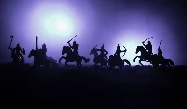 Escena de batalla medieval con caballería e infantería. Siluetas de figuras como objetos separados, lucha entre guerreros sobre fondo de niebla tonificado oscuro. Escena nocturna . — Foto de Stock