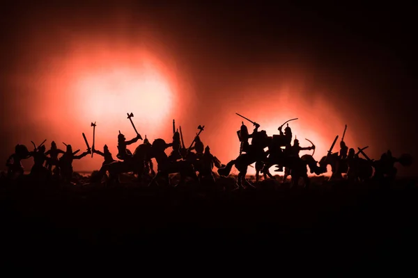 Escena de batalla medieval con caballería e infantería. Siluetas de figuras como objetos separados, lucha entre guerreros sobre fondo de niebla tonificado oscuro. Escena nocturna . — Foto de Stock