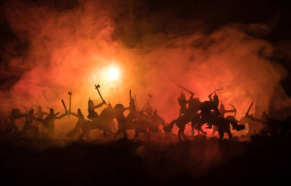 Medieval battle scene with cavalry and infantry. Silhouettes of figures as separate objects, fight between warriors on dark toned foggy background. Night scene.