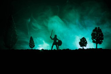 Süvari ve piyade ile ortaçağ savaş sahnesi. Siluetleri şekiller ayrı nesneler olarak mücadele koyu tonda sisli arka plan savaşçılar arasında. Gece çekimi.