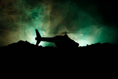 Askeri helikopter çatışma bölgesinden uçmaya hazır silüeti. Gece görüntüleri çöl sisli tonda sırt ile başlayarak helikopter ile dekore edilmiştir. Seçici odak.