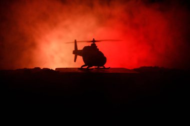 Askeri helikopter çatışma bölgesinden uçmaya hazır silüeti. Gece görüntüleri çöl sisli tonda sırt ile başlayarak helikopter ile dekore edilmiştir. Seçici odak.