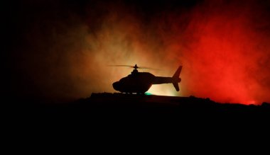 Askeri helikopter çatışma bölgesinden uçmaya hazır silüeti. Gece görüntüleri çöl sisli tonda sırt ile başlayarak helikopter ile dekore edilmiştir. Seçici odak.