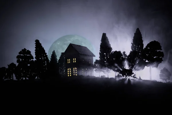 Antigua casa con un Fantasma en el bosque por la noche o Casa de terror embrujada abandonada en la niebla. Antiguo edificio místico en el bosque de árboles muertos. Árboles en la noche con luna. Luces surrealistas — Foto de Stock