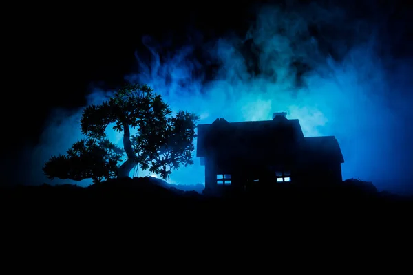 Old house with a Ghost in the forest at night or Abandoned Haunted Horror House in fog. Old mystic building in dead tree forest. Trees at night with moon. Surreal lights