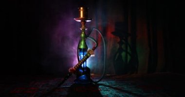 Nargile kömürü nargile kupa Arap iç de buhar bulutları yapma. Şark süsleme halı üzerinde. Şık oryantal shisha içinde karanlık arka ışık ile. Shisha dönme göstermek üzerinde. Kaymak vurdu