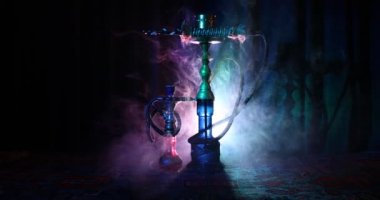 Nargile kömürü nargile kupa Arap iç de buhar bulutları yapma. Şark süsleme halı üzerinde. Şık oryantal shisha içinde karanlık arka ışık ile. Shisha dönme göstermek üzerinde. Kaymak vurdu