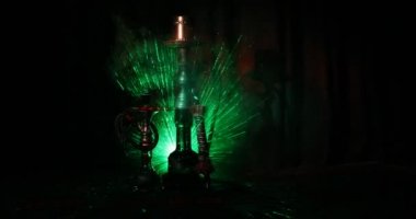 Nargile kömürü nargile kupa Arap iç de buhar bulutları yapma. Şark süsleme halı üzerinde. Şık oryantal shisha içinde karanlık arka ışık ile. Shisha dönme göstermek üzerinde. Kaymak vurdu