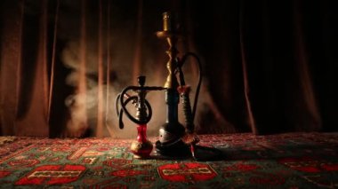 Nargile kömürü nargile kupa Arap iç de buhar bulutları yapma. Şark süsleme halı üzerinde. Şık oryantal shisha içinde karanlık arka ışık ile. Shisha dönme göstermek üzerinde. Kaymak vurdu