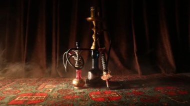 Nargile kömürü nargile kupa Arap iç de buhar bulutları yapma. Şark süsleme halı üzerinde. Şık oryantal shisha içinde karanlık arka ışık ile. Shisha dönme göstermek üzerinde. Kaymak vurdu