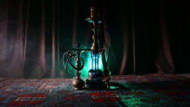 Nargile kömürü nargile kupa Arap iç de buhar bulutları yapma. Şark süsleme halı üzerinde. Şık oryantal shisha içinde karanlık arka ışık ile. Shisha dönme göstermek üzerinde. Kaymak vurdu