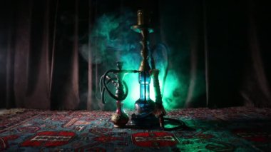 Nargile kömürü nargile kupa Arap iç de buhar bulutları yapma. Şark süsleme halı üzerinde. Şık oryantal shisha içinde karanlık arka ışık ile. Shisha dönme göstermek üzerinde. Kaymak vurdu