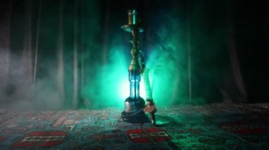 Nargile kömürü nargile kupa Arap iç de buhar bulutları yapma. Şark süsleme halı üzerinde. Şık oryantal shisha içinde karanlık arka ışık ile. Shisha dönme göstermek üzerinde. Kaymak vurdu