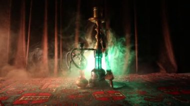 Nargile kömürü nargile kupa Arap iç de buhar bulutları yapma. Şark süsleme halı üzerinde. Şık oryantal shisha içinde karanlık arka ışık ile. Shisha dönme göstermek üzerinde. Kaymak vurdu