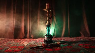 Nargile kömürü nargile kupa Arap iç de buhar bulutları yapma. Şark süsleme halı üzerinde. Şık oryantal shisha içinde karanlık arka ışık ile. Shisha dönme göstermek üzerinde. Kaymak vurdu