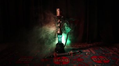 Nargile kömürü nargile kupa Arap iç de buhar bulutları yapma. Şark süsleme halı üzerinde. Şık oryantal shisha içinde karanlık arka ışık ile. Shisha dönme göstermek üzerinde. Kaymak vurdu