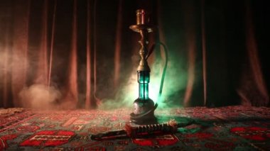 Nargile kömürü nargile kupa Arap iç de buhar bulutları yapma. Şark süsleme halı üzerinde. Şık oryantal shisha içinde karanlık arka ışık ile. Shisha dönme göstermek üzerinde. Kaymak vurdu