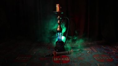 Nargile kömürü nargile kupa Arap iç de buhar bulutları yapma. Şark süsleme halı üzerinde. Şık oryantal shisha içinde karanlık arka ışık ile. Shisha dönme göstermek üzerinde. Kaymak vurdu
