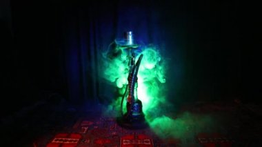 Nargile kömürü nargile kupa Arap iç de buhar bulutları yapma. Şark süsleme halı üzerinde. Şık oryantal shisha içinde karanlık arka ışık ile. Shisha dönme göstermek üzerinde. Kaymak vurdu