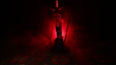 Nargile kömürü nargile kupa Arap iç de buhar bulutları yapma. Şark süsleme halı üzerinde. Şık oryantal shisha içinde karanlık arka ışık ile. Shisha dönme göstermek üzerinde. Kaymak vurdu