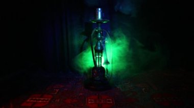 Nargile kömürü nargile kupa Arap iç de buhar bulutları yapma. Şark süsleme halı üzerinde. Şık oryantal shisha içinde karanlık arka ışık ile. Shisha dönme göstermek üzerinde. Kaymak vurdu