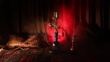 Nargile kömürü nargile kupa Arap iç de buhar bulutları yapma. Şark süsleme halı üzerinde. Şık oryantal shisha içinde karanlık arka ışık ile. Shisha dönme göstermek üzerinde. Kaymak vurdu