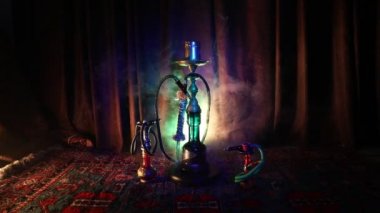 Nargile kömürü nargile kupa Arap iç de buhar bulutları yapma. Şark süsleme halı üzerinde. Şık oryantal shisha içinde karanlık arka ışık ile. Shisha dönme göstermek üzerinde. Kaymak vurdu