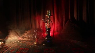 Nargile kömürü nargile kupa Arap iç de buhar bulutları yapma. Şark süsleme halı üzerinde. Şık oryantal shisha içinde karanlık arka ışık ile. Shisha dönme göstermek üzerinde. Kaymak vurdu