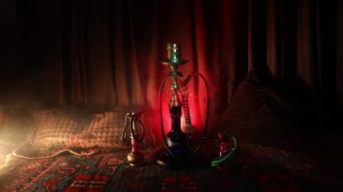 Nargile kömürü nargile kupa Arap iç de buhar bulutları yapma. Şark süsleme halı üzerinde. Şık oryantal shisha içinde karanlık arka ışık ile. Shisha dönme göstermek üzerinde. Kaymak vurdu