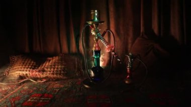 Nargile kömürü nargile kupa Arap iç de buhar bulutları yapma. Şark süsleme halı üzerinde. Şık oryantal shisha içinde karanlık arka ışık ile. Shisha dönme göstermek üzerinde. Kaymak vurdu