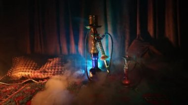 Nargile kömürü nargile kupa Arap iç de buhar bulutları yapma. Şark süsleme halı üzerinde. Şık oryantal shisha içinde karanlık arka ışık ile. Shisha dönme göstermek üzerinde. Kaymak vurdu