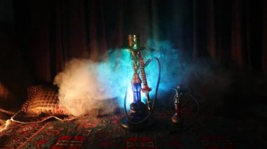 Nargile kömürü nargile kupa Arap iç de buhar bulutları yapma. Şark süsleme halı üzerinde. Şık oryantal shisha içinde karanlık arka ışık ile. Shisha dönme göstermek üzerinde. Kaymak vurdu
