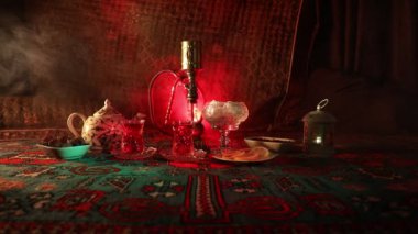 Nargile kömürü nargile kupa Arap iç de buhar bulutları yapma. Şark süsleme halı Doğu çay töreni üzerinde. Şık oryantal shisha içinde karanlık arka ışık ile. Kaymak vurdu