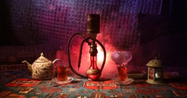 Nargile kömürü nargile kupa Arap iç de buhar bulutları yapma. Şark süsleme halı Doğu çay töreni üzerinde. Şık oryantal shisha içinde karanlık arka ışık ile. Kaymak vurdu