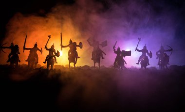 Süvari ve piyade ile ortaçağ savaş sahnesi. Siluetleri şekiller ayrı nesneler olarak mücadele koyu tonda sisli arka plan savaşçılar arasında. Gece çekimi.