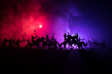 Süvari ve piyade ile ortaçağ savaş sahnesi. Siluetleri şekiller ayrı nesneler olarak mücadele koyu tonda sisli arka plan savaşçılar arasında. Gece çekimi.