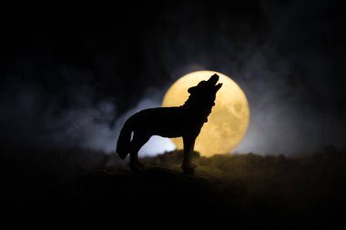 Siluet karanlık karşı uluyan kurt sisli arka plan ve dolunay ya da kurt tam aya inleyen siluet tonda. Halloween korku kavramı.