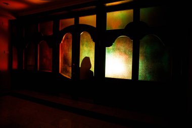 Bir bilinmeyen gölge figürü bir kapı bir kapalı cam kapıdan silüeti. Geceleri bir pencerenin önünde bir insan silüeti. Korkunç sahne Cadılar Bayramı kavramı bulanık silueti