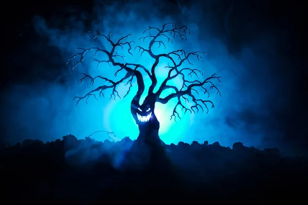 Silueta strašidelný Halloween stromu s hrůzou tváří v mlhavé tmě laděných pozadí se měsíc na zadní straně. Děsivý horor strom s zombie a démon tváře. — Stock fotografie