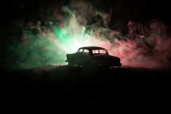 Sylwetka starego rocznika samochodu w ciemności mglisty stonowanych tło z świecące światła w słabym świetle, lub starych sylwetka przestępstwa samochodowe ciemne tło. — Zdjęcie stockowe