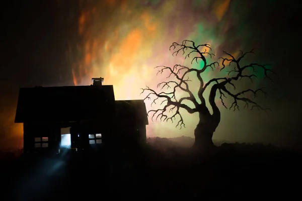 Casa velha com um fantasma à noite com árvore assustadora ou abandonada Haunted Horror House em tonificado céu nebuloso com luz. Um velho edifício místico numa floresta de árvores mortas. Conceito de Halloween . — Fotografia de Stock