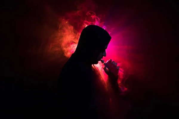 Hombre aspirante sosteniendo un mod. Una nube de vapor. Fondo negro. Vapeando un cigarrillo electrónico con mucho humo. Concepto de Vape — Foto de Stock