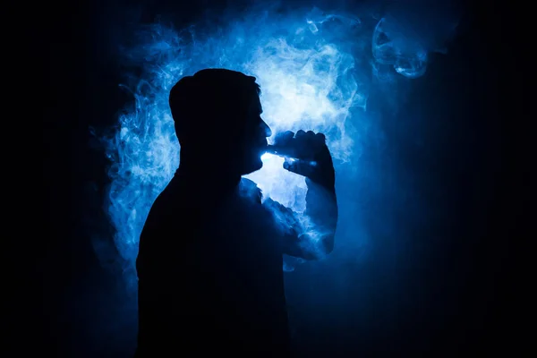 Vaping mężczyzna trzymając mod. Chmurę pary wodnej. Czarne tło. Vaping elektroniczny papieros z dużo dymu. Koncepcja Vape — Zdjęcie stockowe