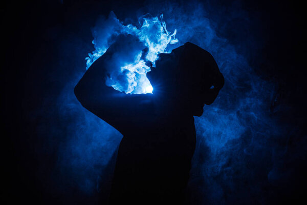 Vaping man holding a mod. A cloud of vapor. Black background. Vaping an electronic cigarette with a lot of smoke. Vape concept
