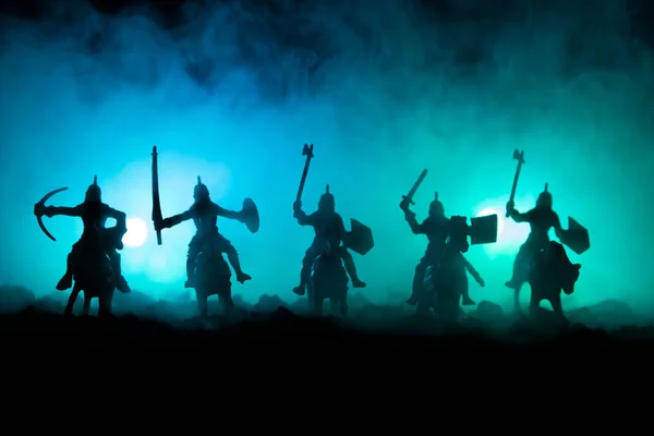 Escena de batalla medieval con caballería e infantería. Siluetas de figuras como objetos separados, lucha entre guerreros sobre fondo de niebla tonificado oscuro. Escena nocturna . — Foto de Stock