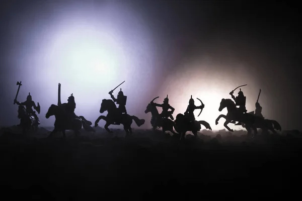Middeleeuwse slag scène met de cavalerie en infanterie. Silhouetten van figuren als afzonderlijke objecten, strijd tussen krijgers op donker getinte mistige achtergrond. Nachtbeeld. — Stockfoto