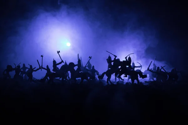 Adegan pertempuran abad pertengahan dengan kavaleri dan infanteri. Siluet figur sebagai objek terpisah, bertarung antara prajurit dengan latar belakang berkabut gelap. Adegan malam . — Stok Foto